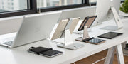 Multiple iPads charging on various stands on an organized desk.