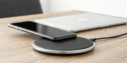 Sleek luxury wireless charger for a modern home charging a smartphone on a wooden desk.