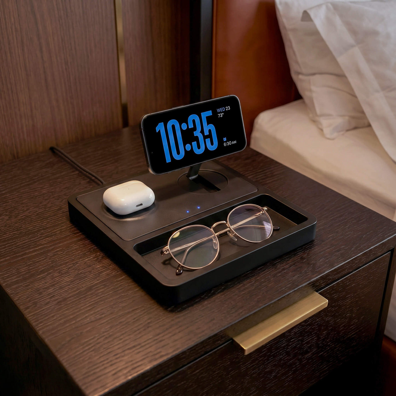 iPhone on a MagSafe wireless charging station on a premium wood desk with soft warm lighting