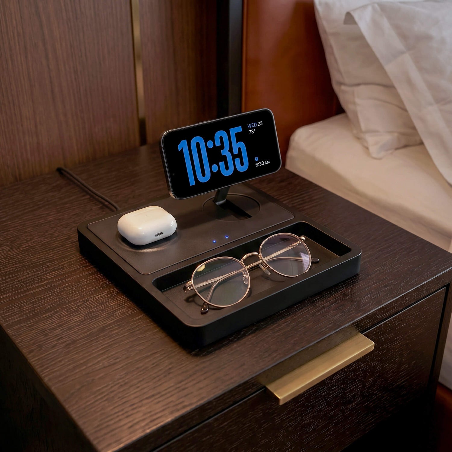 iPhone on a MagSafe wireless charging station on a premium wood desk with soft warm lighting