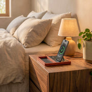 Handcrafted wood and leather charging station holding an iPhone and AirPods in a warm modern home setting