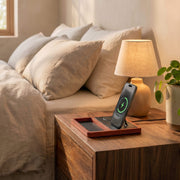 A handcrafted walnut wood wireless charging station with an iPhone resting on a magnetic charger in warm ambient light