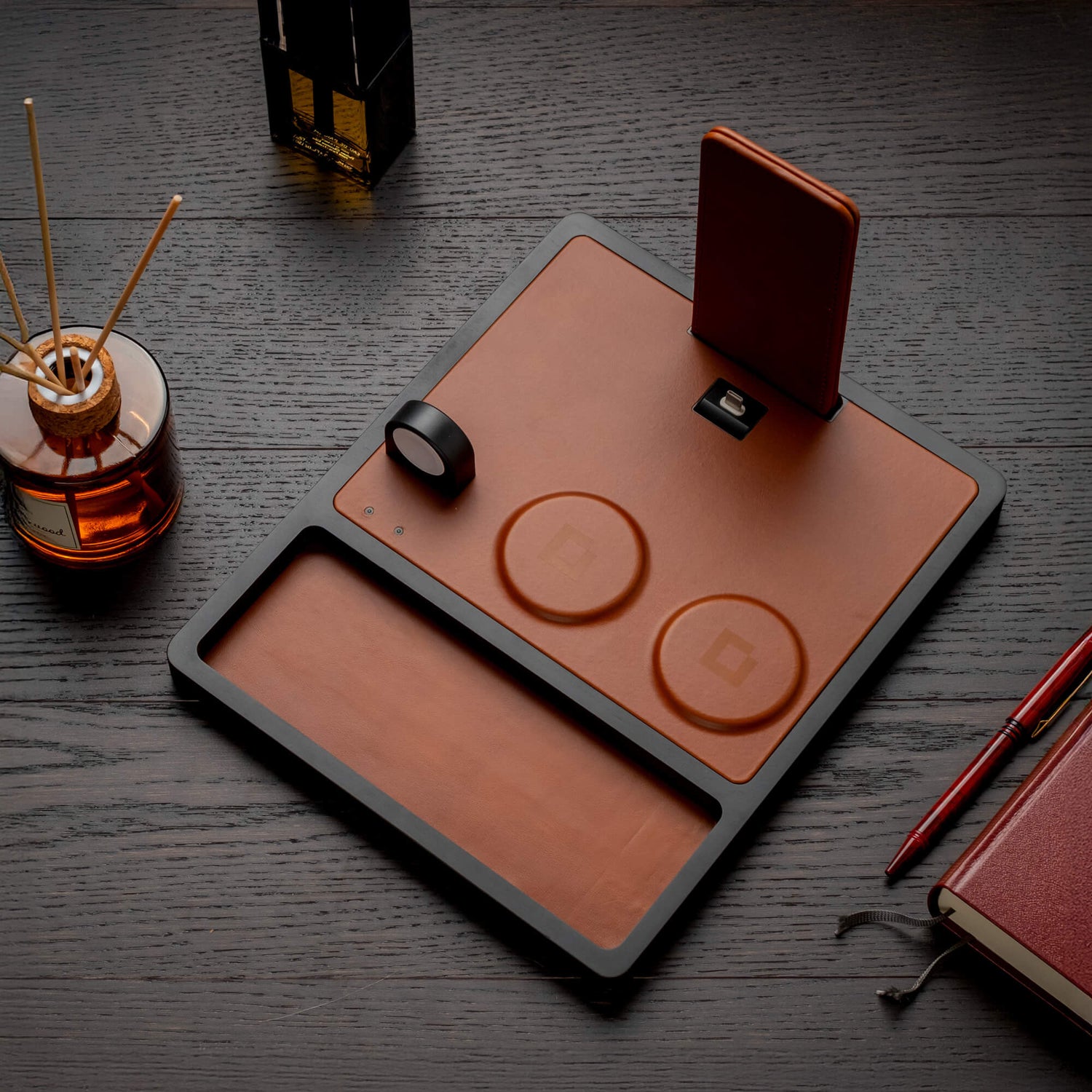 A wood and leather wireless charging station for a phone and tablet on a desk.