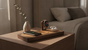 Premium wood and leather all-in-one charging station on a nightstand charging iPhone, Apple Watch, and AirPods