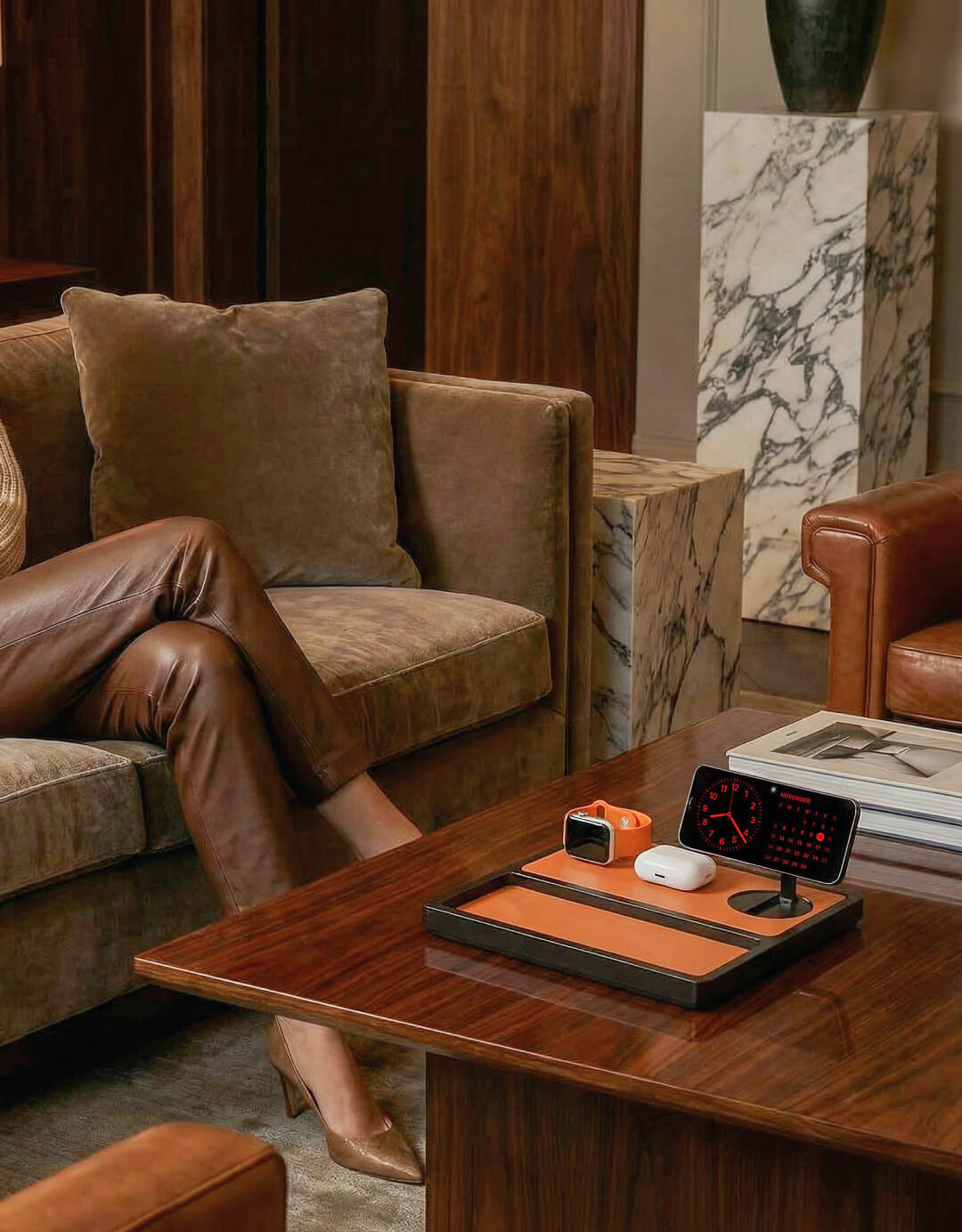 Saddle brown leather charging dock with Apple devices on a wood desk