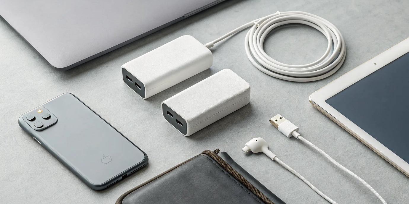 A single PD wall charger powering a laptop, smartphone, and tablet on a desk.