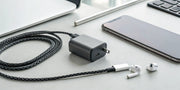 A compact 33W USB C charger fast charging a smartphone and wireless earbuds.
