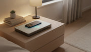 Qi2 wireless charging station with iPhone on wooden nightstand