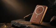 Slim MagSafe power bank attached to iPhone on a dark wood desk beside a leather wallet
