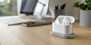 AirPods charging on a sleek, modern stand on an organized desk.