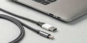 A braided USB C to USB C cable positioned next to a laptop's USB-C port.
