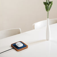 UNO Alcantara Blue - Single-Coil MagSafe Oak Wireless Charger Angle View, charging  AirPods on white table